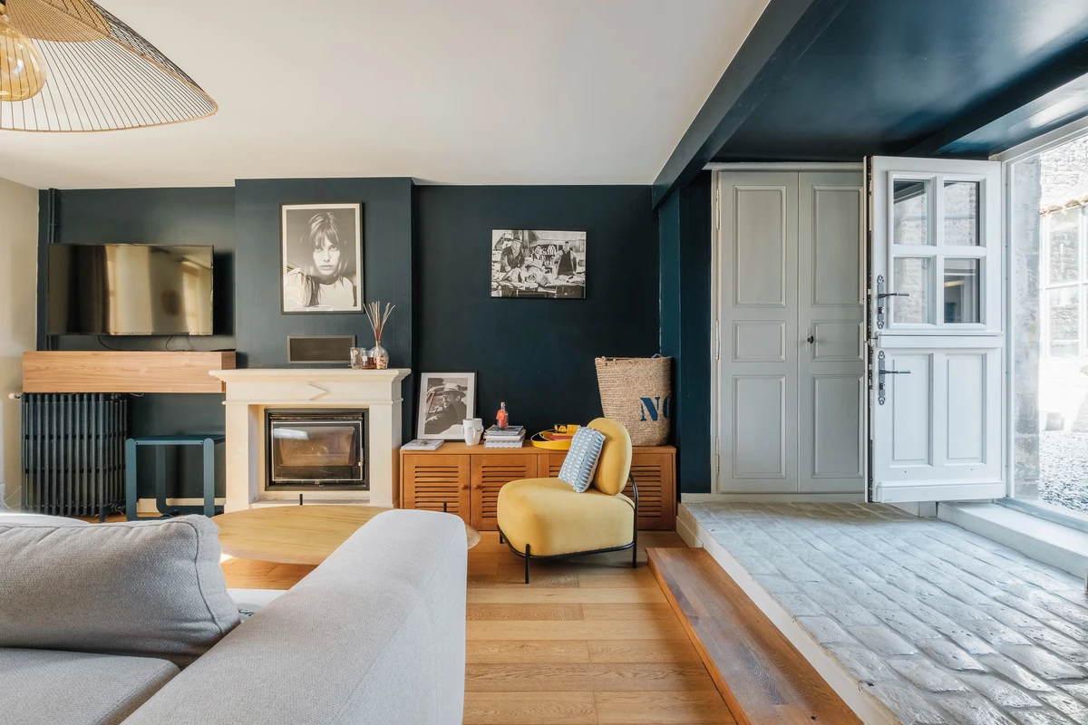 Salon bleu nuit avec cheminée et fauteuil jaune — Espaces Atypiques