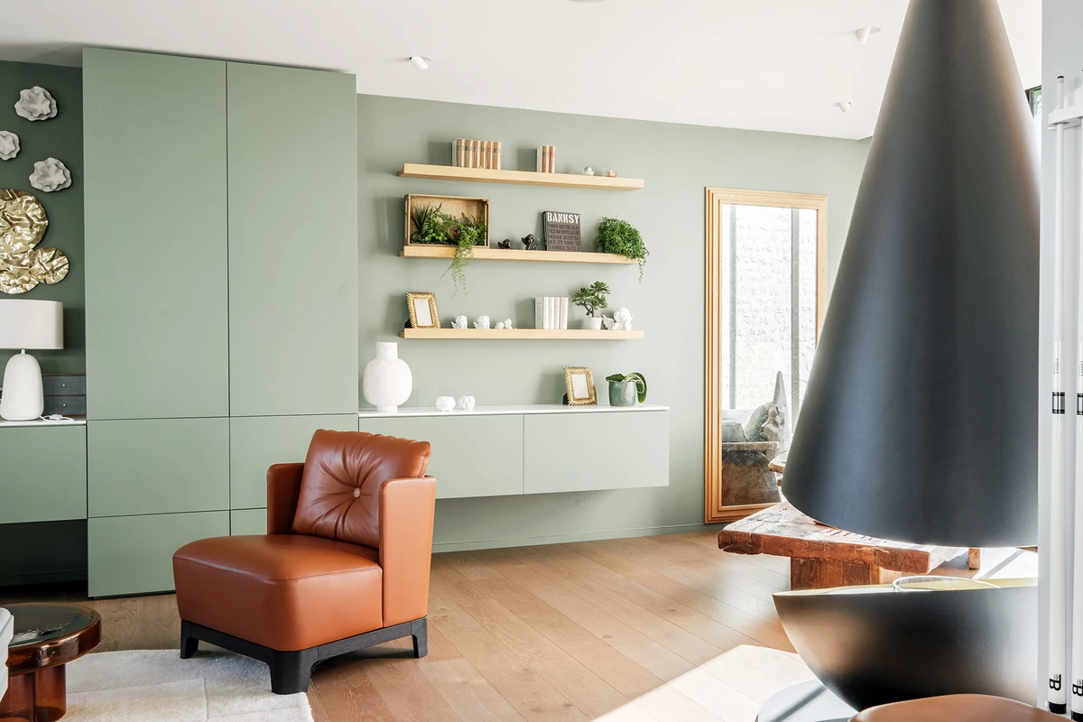 Salon vert sauge, fauteuil cuir et cheminée suspendue — Espaces Atypiques